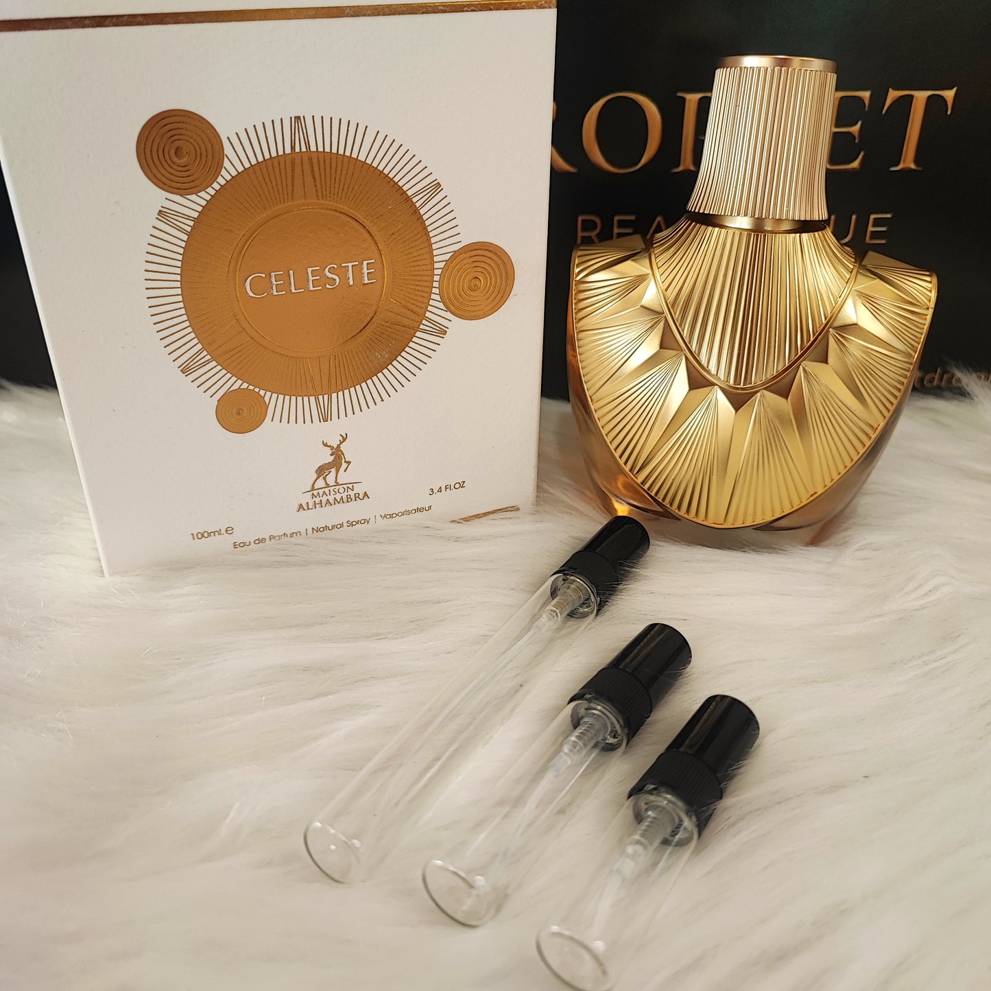 Celeste by Maison Alhambra decant samples with bottle and box on white fur
